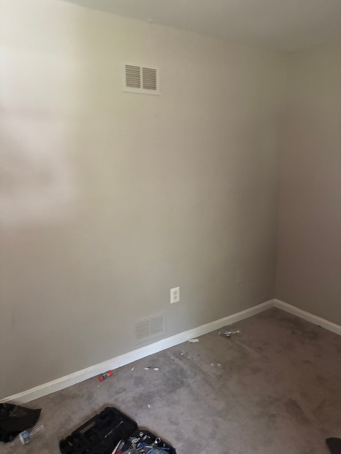Empty bedroom with beige walls and gray carpet after furniture removal and cleanout