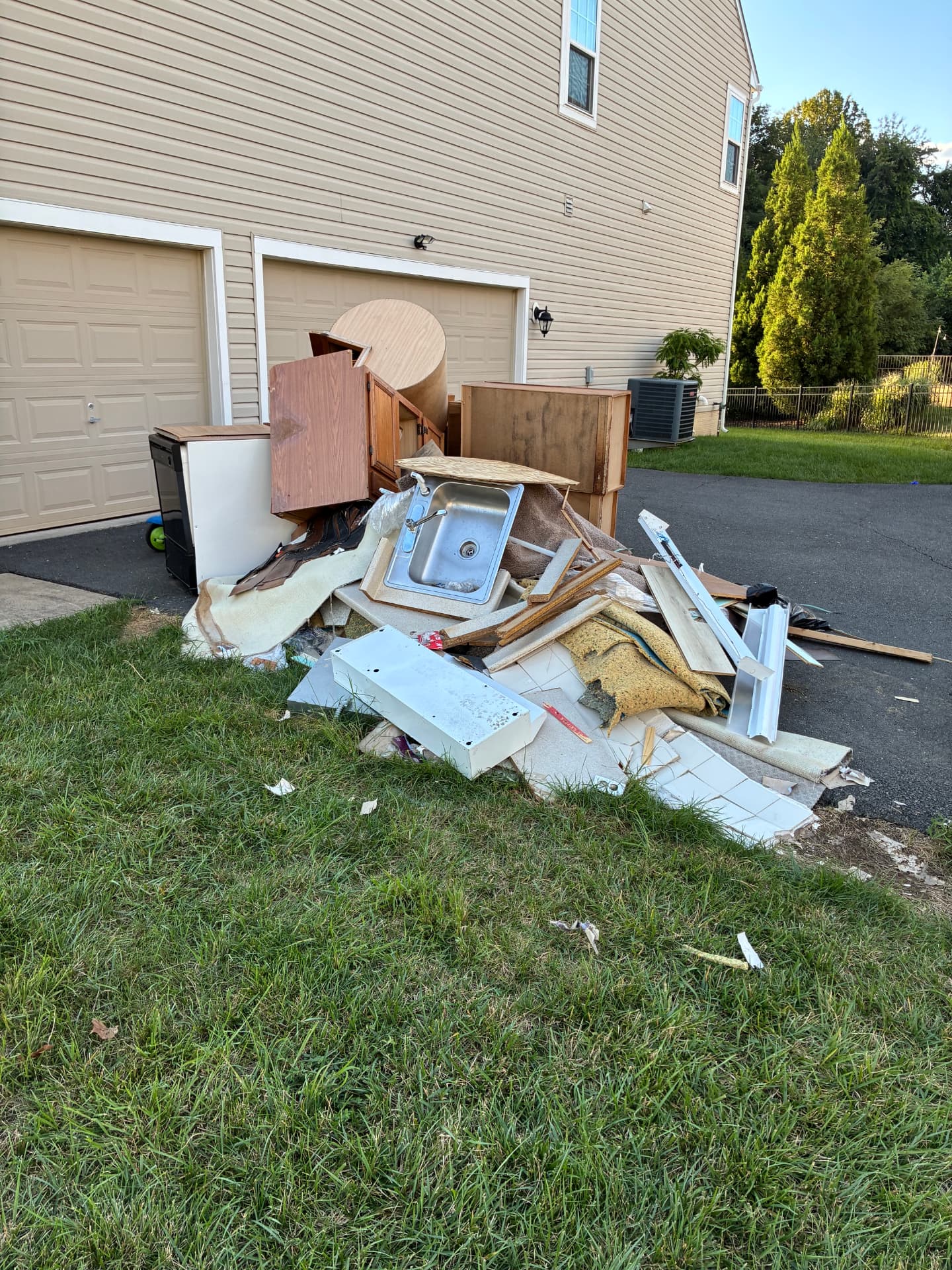 Pile of construction debris, cabinets and old sink on a driveway in Aldie, VA before removal